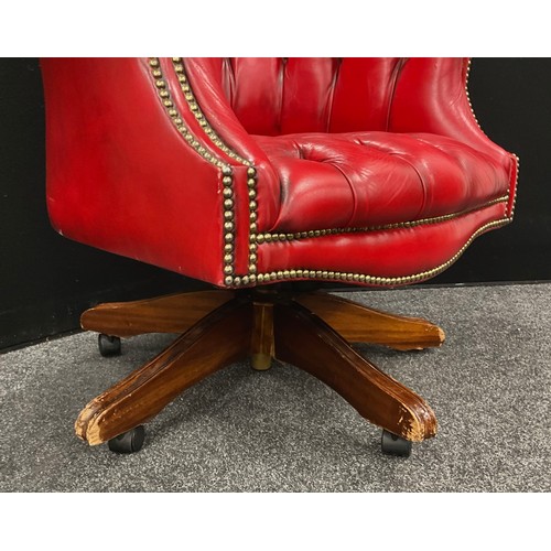 106 - A chesterfield office chair, ox-blood red leather, button-back, rotating, rise-and-fall base.