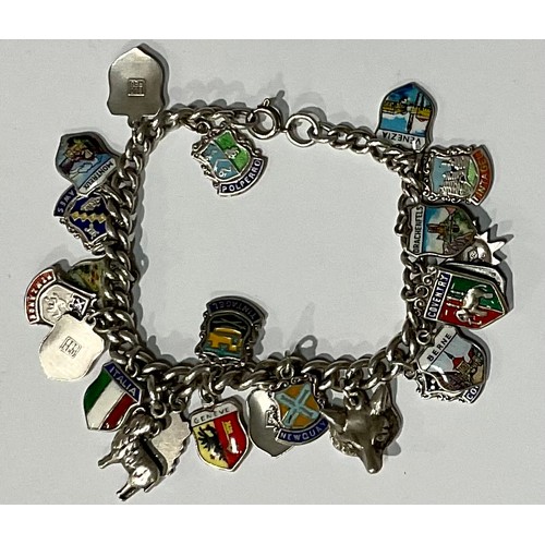 565 - A silver charm bracelet, with 23 mostly silver and enamel charms, 44.4g gross