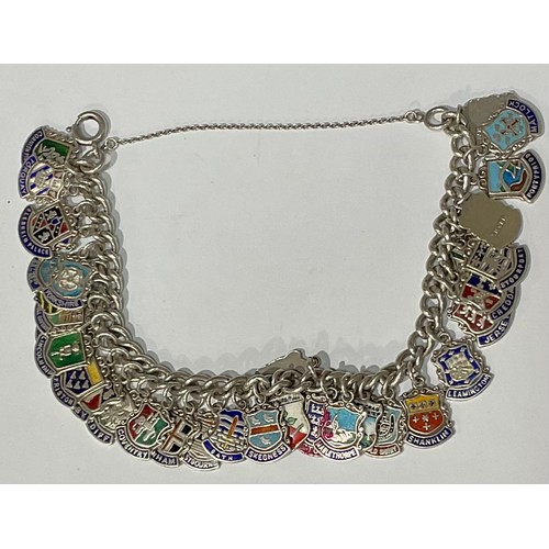 568 - A silver charm bracelet, with 34 mostly silver and enamel charms, 61.2g gross