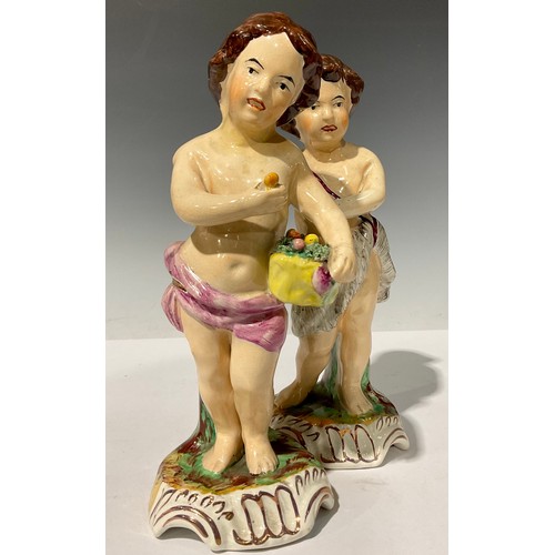 674 - A pair of 19th century Staffordshire figures, each as putti with baskets of fruit, in polychrome, sh... 