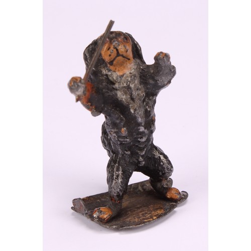 695 - An early 20th century painted metal model, Spaniel conductor, standing holding a musical baton, indi... 