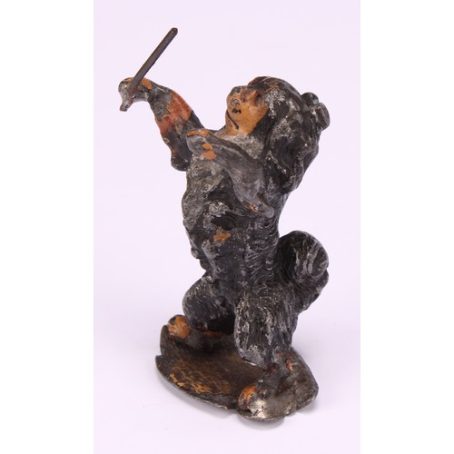 695 - An early 20th century painted metal model, Spaniel conductor, standing holding a musical baton, indi... 