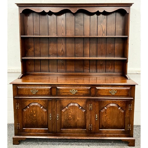 177 - An oak dresser, two tier plate rack above three frieze drawers and three arched panel doors, brass h... 