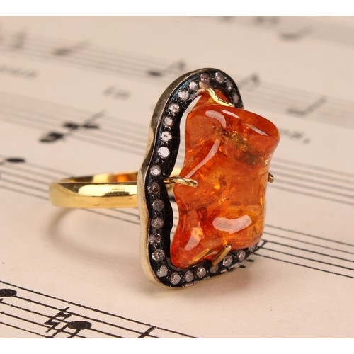 263 - An 18ct gold and silver topped ring set with a freeform mandarin garnet surrounded vby rose cut diam... 