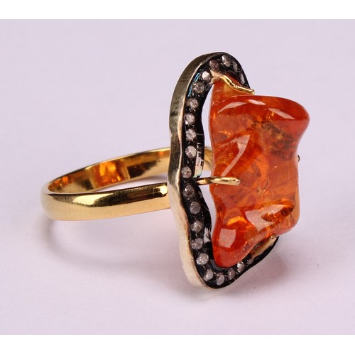 263 - An 18ct gold and silver topped ring set with a freeform mandarin garnet surrounded vby rose cut diam... 