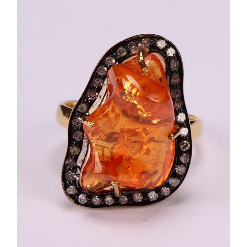 263 - An 18ct gold and silver topped ring set with a freeform mandarin garnet surrounded vby rose cut diam... 