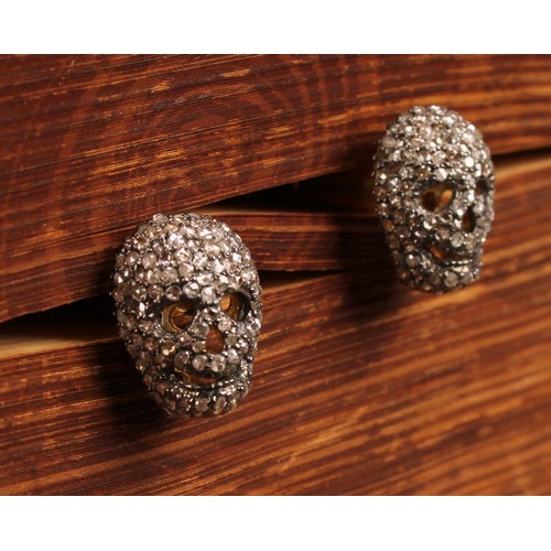 264 - The Macabre - a pair of diamond encrusted novelty cufflinks, as skulls, each set with rose cut stone... 