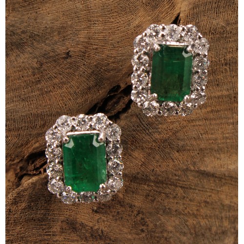 265 - A pair of 18ct white gold cluster earrings set with step-cut emeralds and round brilliant cut diamon... 