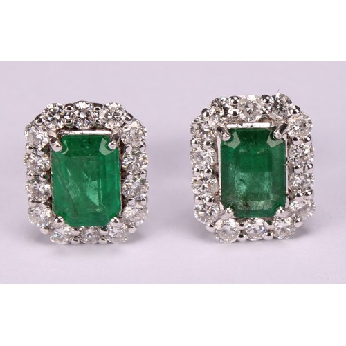 265 - A pair of 18ct white gold cluster earrings set with step-cut emeralds and round brilliant cut diamon... 