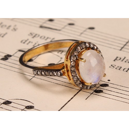 272 - A moonstone and diamond ring, the large Oval cabochon rainbow moonstone within a border of rose-cut ... 