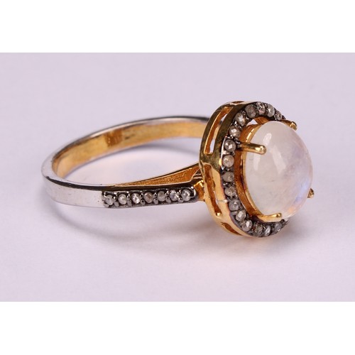 272 - A moonstone and diamond ring, the large Oval cabochon rainbow moonstone within a border of rose-cut ... 