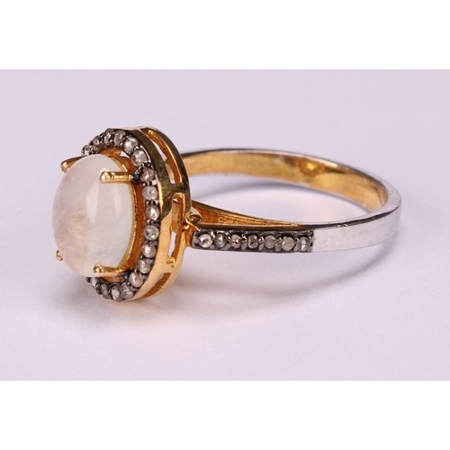 272 - A moonstone and diamond ring, the large Oval cabochon rainbow moonstone within a border of rose-cut ... 