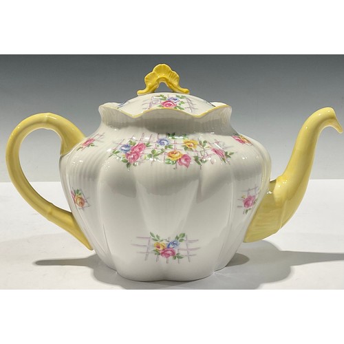 63 - A Shelley teapot, decorated with flowers on a trellis, yellow handle and spout, 25cm long