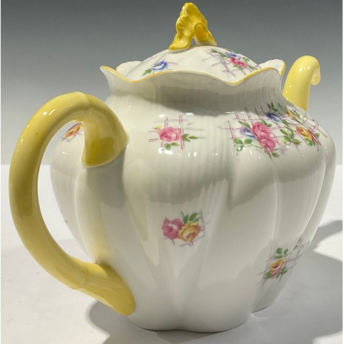 63 - A Shelley teapot, decorated with flowers on a trellis, yellow handle and spout, 25cm long