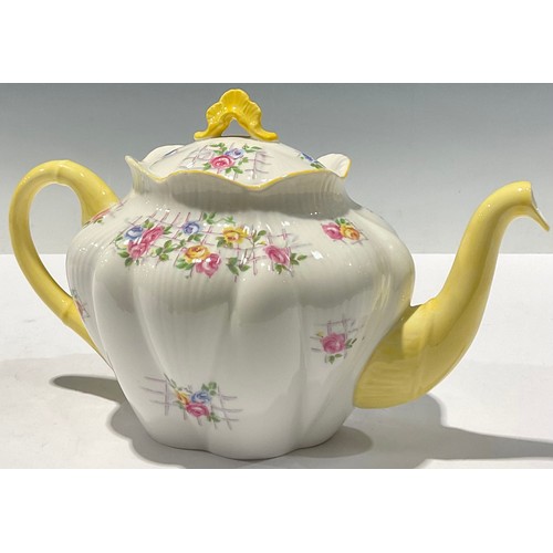 63 - A Shelley teapot, decorated with flowers on a trellis, yellow handle and spout, 25cm long