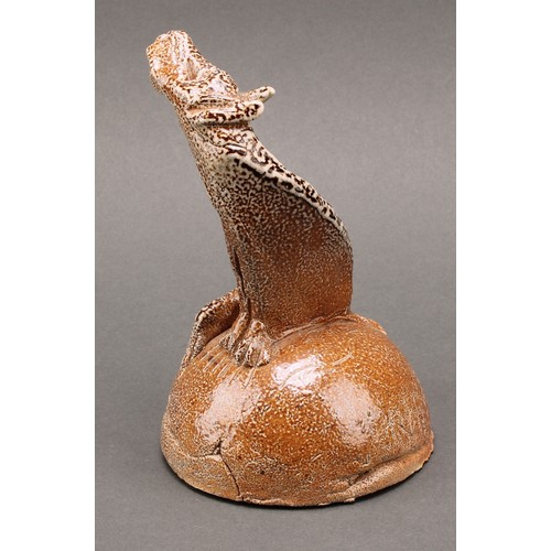 3197 - Studio pottery - a salt glazed stoneware model of a howling hound, seated upon a mound, by Ian Grego... 