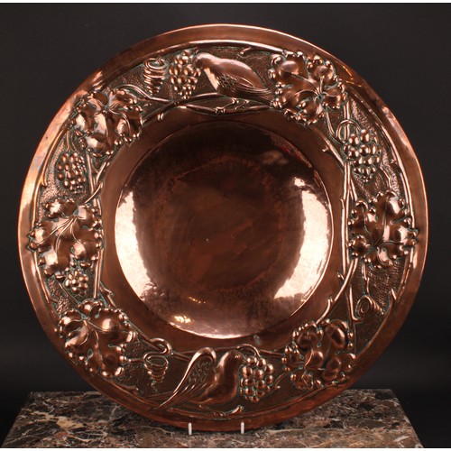 3249 - A large Arts and Crafts copper charger, repousse chased with a band of birds and fruiting vine, 58cm... 