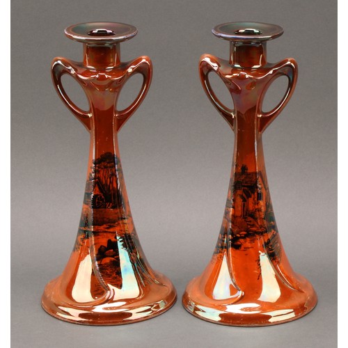 3132 - A pair of Shelley Art Nouveau style orange lustre candlesticks, decorated with cottage and watermill... 