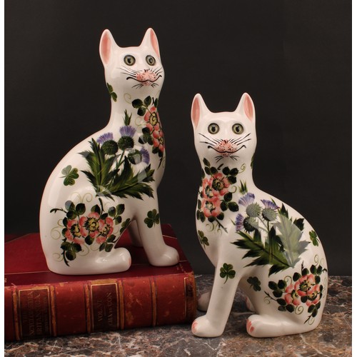 3033 - A pair of Griselda Hill Pottery ceramic cat models, painted with brightly coloured thistle and clove... 