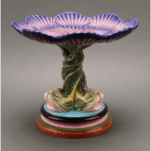 3077 - A Portuguese Majolica ware tazza or cake stand, the shell shaped plate supported by a triform dolphi... 