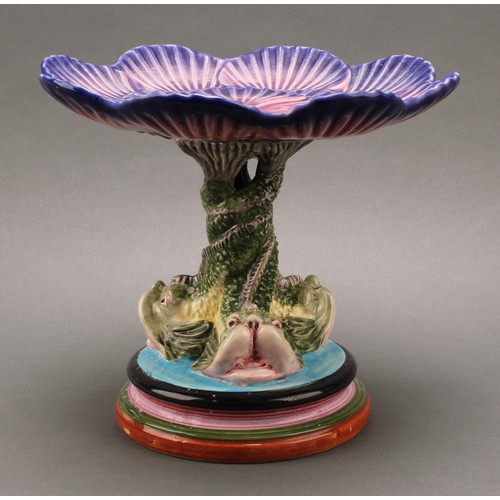 3077 - A Portuguese Majolica ware tazza or cake stand, the shell shaped plate supported by a triform dolphi... 