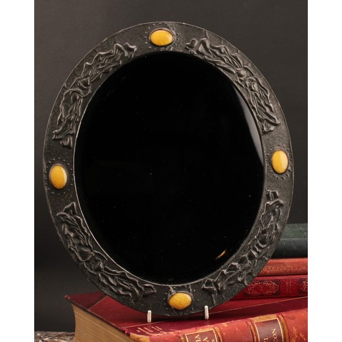 3404 - An Arts & Crafts sheet pewter and simulated ‘Ruskin stone’ mounted oval looking glass, bevelled mirr... 