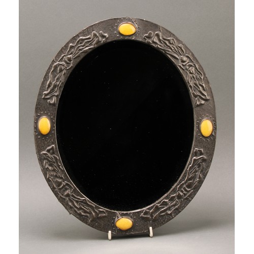 3404 - An Arts & Crafts sheet pewter and simulated ‘Ruskin stone’ mounted oval looking glass, bevelled mirr... 