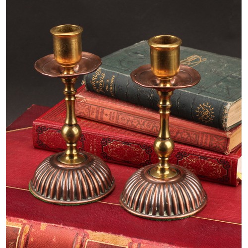 3337 - A pair of Arts and Crafts copper and brass candlesticks, in the Christopher Dresser taste, 15cm high... 