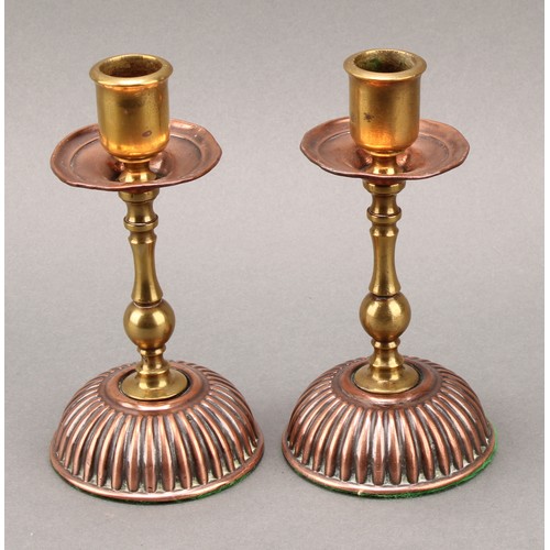 3337 - A pair of Arts and Crafts copper and brass candlesticks, in the Christopher Dresser taste, 15cm high... 