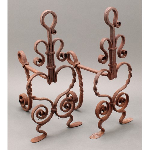 3369 - A pair of Arts and Crafts wrought iron fire dogs or andirons, worked with scrolls and heart shaped m... 