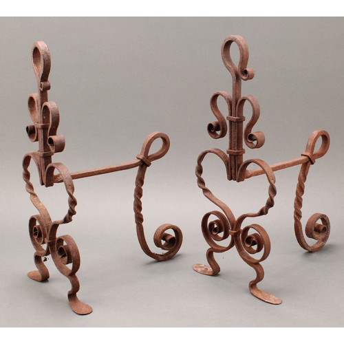 3369 - A pair of Arts and Crafts wrought iron fire dogs or andirons, worked with scrolls and heart shaped m... 