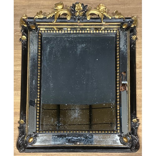 439 - A Baroque style parcel gilt and ebonised looking glass, floral cresting with a pair of birds over pr... 