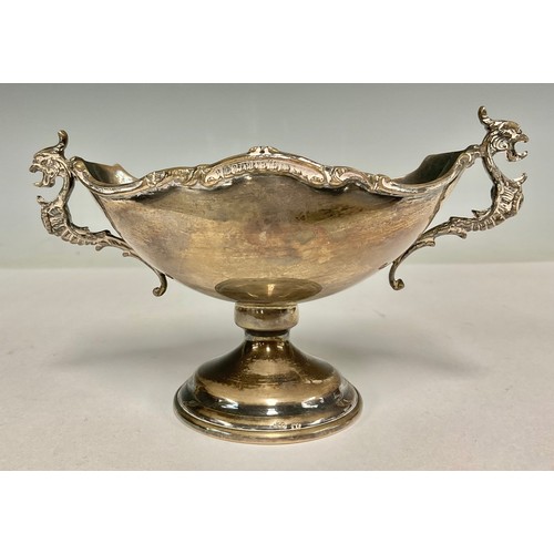 5075 - A Continental silver boat shaped pedestal bowl, the handles as mythical beast, shaped rim chased wit... 