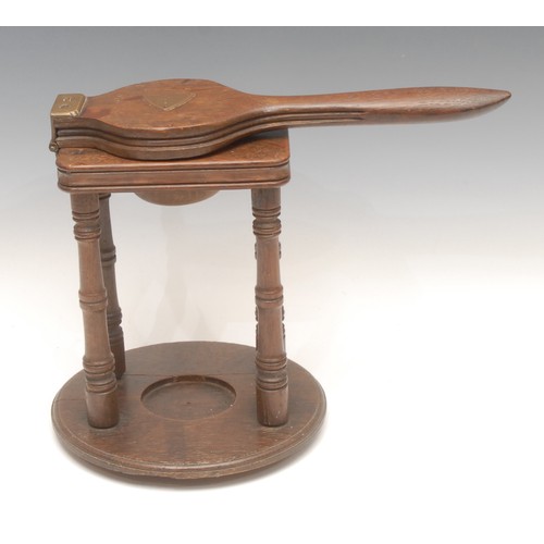 1031 - Treen - a Victorian oak lemon squeezer on stand, brass hinges, turned legs, circular base, 25cm high... 