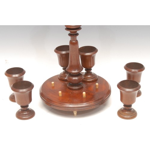 1032 - Treen - an Edwardian mahogany egg cup stand, bone carrying loop above turned column surrounded by si... 