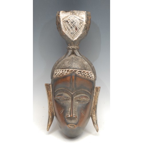 11 - Tribal Art - a Baule mask, concave profile with central ridge and eliptical features, elaborate coif... 