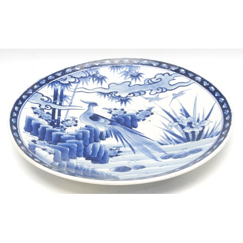 992 - A Japanese circular charger, painted in tones of underglaze blue, with a pheasant perched on a rocky... 