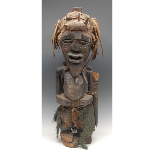 81 - Tribal Art - a Songye Nkisi power or fetish figure, pounted face with stylised eliptical features, a... 