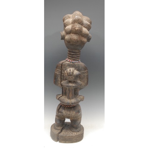 9 - Tribal Art - a Baule fertility figure, typically depicted kneeling, elaborate coiffure, 70cm high, I... 