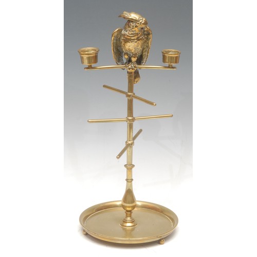 1021 - A 19th century brass cotton reel stand, the cresting cast with a cockatoo, glass eyes, flanked by a ... 