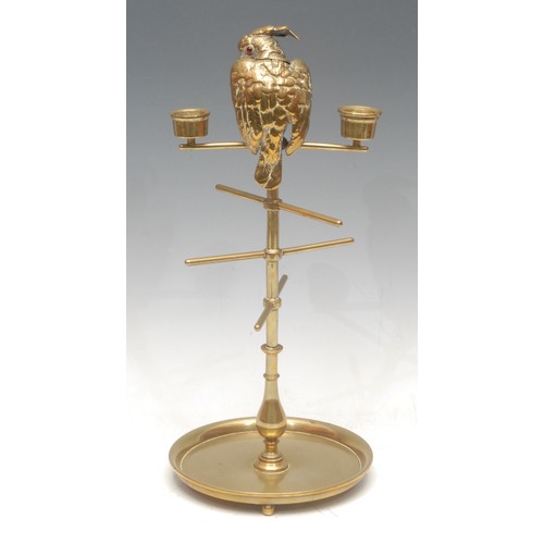 1021 - A 19th century brass cotton reel stand, the cresting cast with a cockatoo, glass eyes, flanked by a ... 