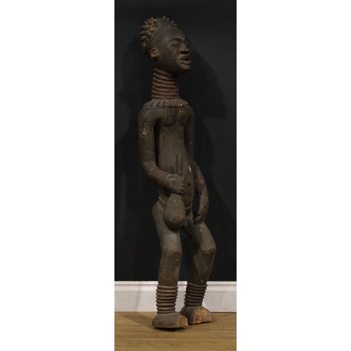 45 - Tribal Art - a large Bangwa/Bamileke figure, he stands, holding an implement, 122cm high, Cameroon