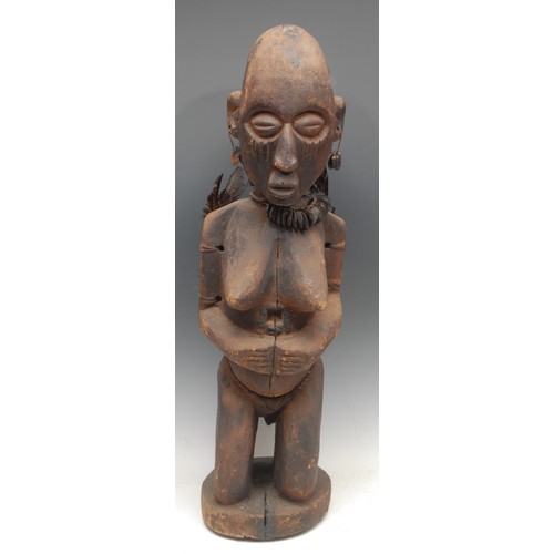 49 - Tribal Art - a large Yoruba figure, female, kneeling, adorned with feathers, and a pod necklace, 72c... 