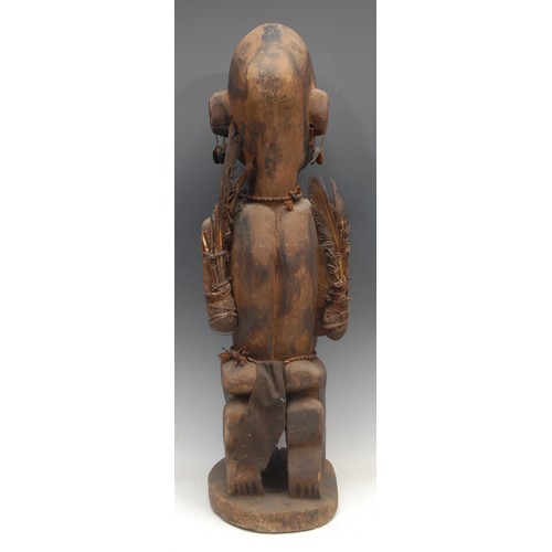 49 - Tribal Art - a large Yoruba figure, female, kneeling, adorned with feathers, and a pod necklace, 72c... 