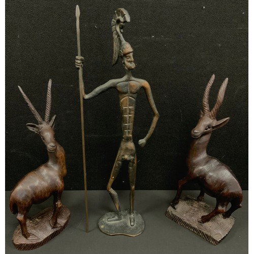 125 - A Bronze figure of a warrior, 44cm high; a pair of treen gazelles, 33cm high, (3).