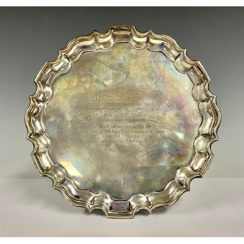 86 - An Edward VII silver shaped circular salver, shaped border, four scroll feet, presentation inscripti... 