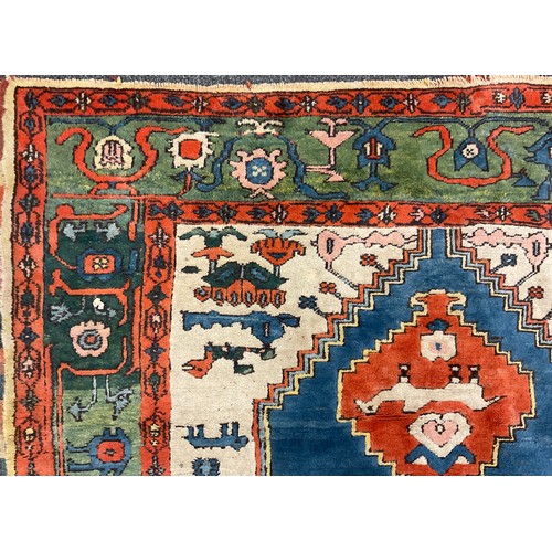 105 - A Turkish Konya rug, hand-knotted in tones of red, blue, green, and white, 247cm x 198 cm.