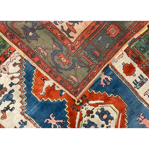 105 - A Turkish Konya rug, hand-knotted in tones of red, blue, green, and white, 247cm x 198 cm.