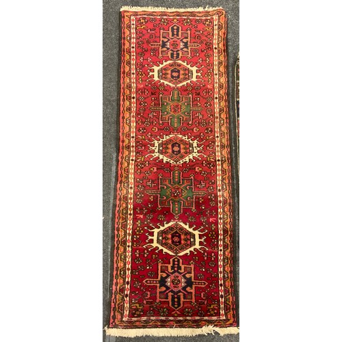 163 - A Persian Heriz type runner carpet, hand-knotted in tones of red, deep brown, white, and pink, 188cm... 