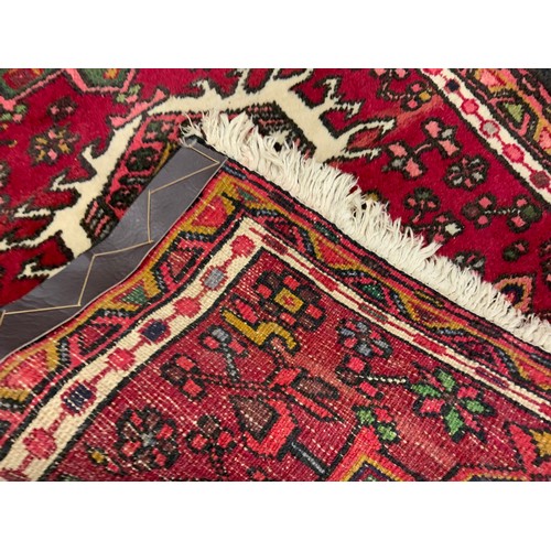 163 - A Persian Heriz type runner carpet, hand-knotted in tones of red, deep brown, white, and pink, 188cm... 